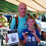 Dad and little boy hold up Don't Be A Boob poster at the farmers market